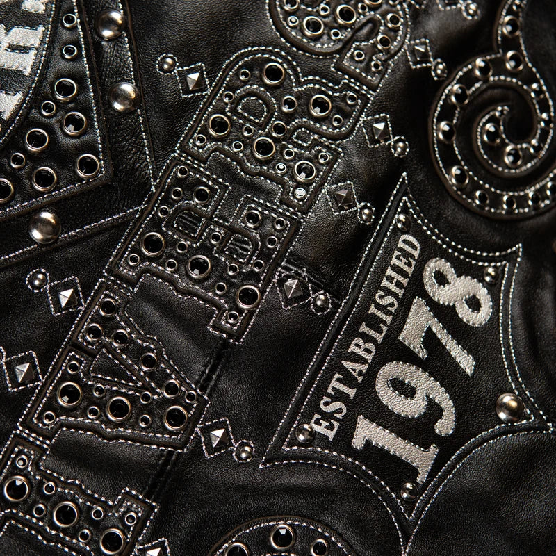 Close-up of the Pelle Pelle Unrivaled Anniversary black jacket showing tonal graphics, decorative studs, and silver-style stitching