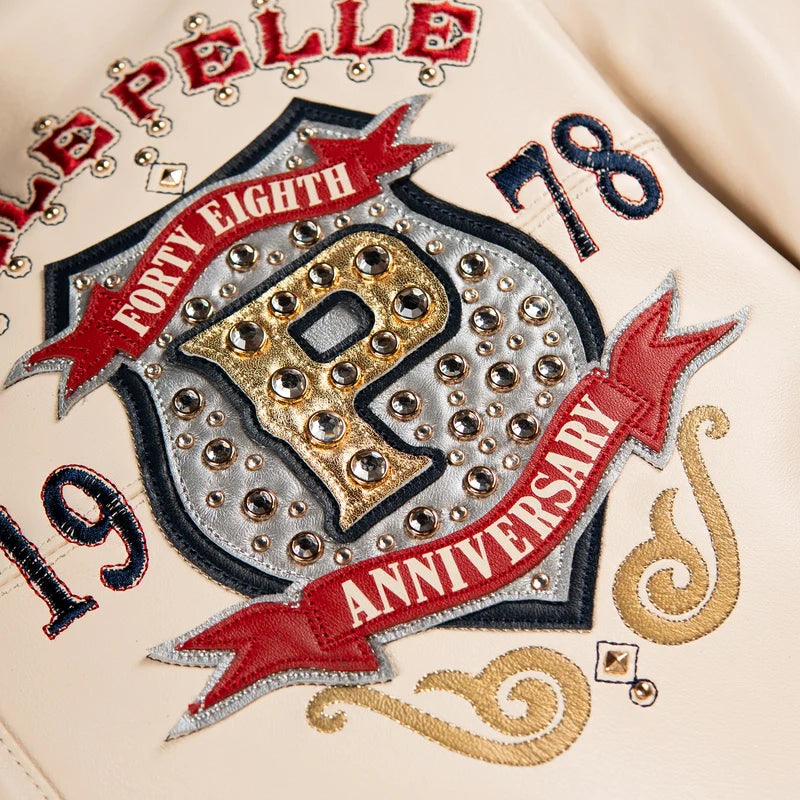 Close-up of the Pelle Pelle Unrivaled Anniversary jacket showing gold-tone lettering, silver details, and decorative studs