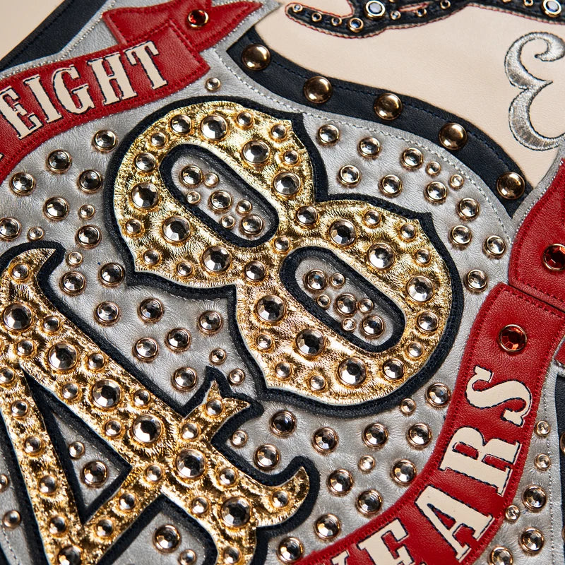 Detailed embellishments on the Pelle Pelle ivory anniversary jacket featuring decorative lettering and metallic-tone accents