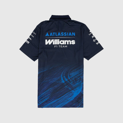 A short-sleeve polo shirt shown from the back, featuring a dark navy base with a blue and black tire-track graphic pattern across the lower half. The back is printed with 'ATLASSIAN Williams F1 TEAM' in white and blue, and the sleeves feature sponsor logos.