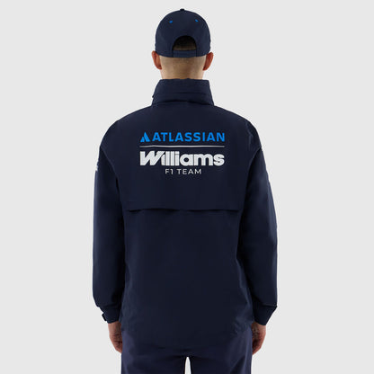 A man viewed from behind wearing a navy blue zip-up jacket and matching cap. The back of the jacket features prominent white and blue 'ATLASSIAN Williams F1 TEAM' branding.