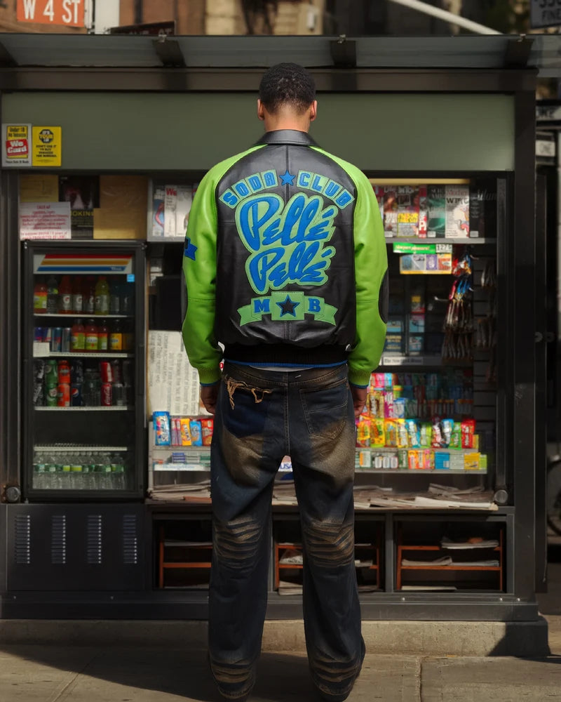 Model wearing a black and lime green Pelle Pelle Soda Club jacket with large blue back lettering and green sleeves