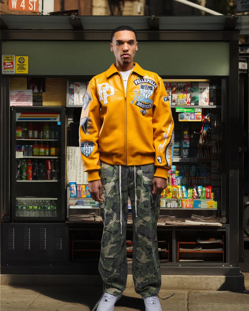 Model wearing a yellow Pelle Pelle American Bruiser graphic jacket with decorative patches and contrasting streetwear details